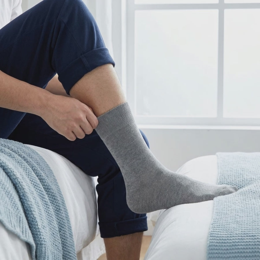 Mies vetää harmaan SockCalm-bambusukan jalkaan ja silittää pehmeän resorin